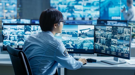 A person sitting at a desk with multiple monitors
Description automatically generated